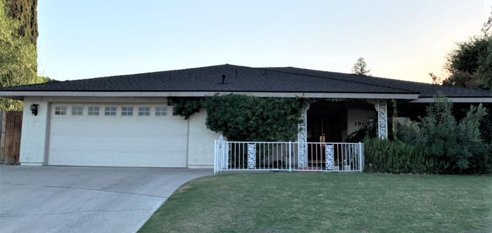 Single-story suburban home with a garage, front porch, and lush landscaping.